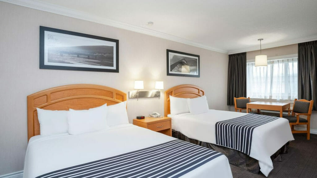 The Corporate Two Queens room includes two queen beds, small fridge, microwave, tea kettle and coffee maker, sitting area, flatscreen TV, hair dryer, iron and ironing board, in-room climate control, desk with lamp and ergonomic chair, and bathroom with complimentary toiletries.